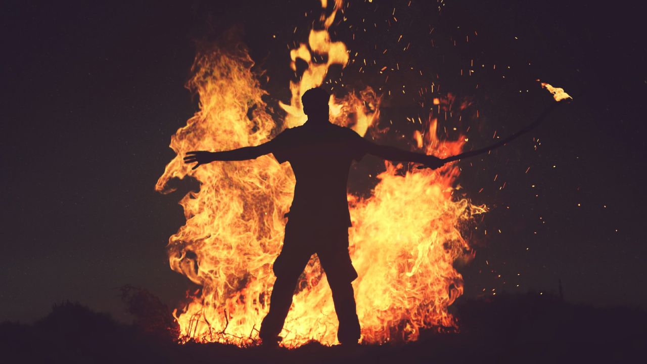 A man standing in front of a roaring fire